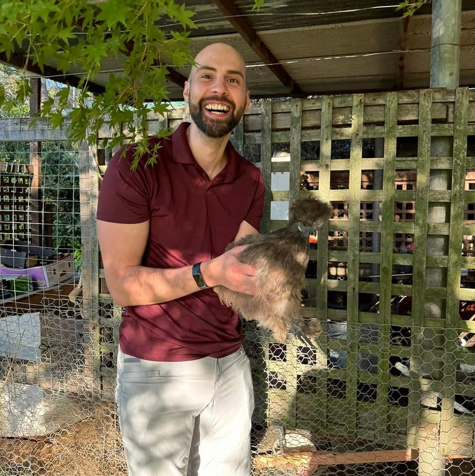 Josh smiling while holding a fluffy chicken